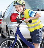 Kind mit Fahrrad zwischen Autos